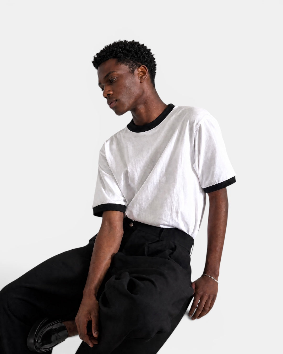 Nameless white cotton t-shirt with black trim on collar and sleeves, worn by a man.