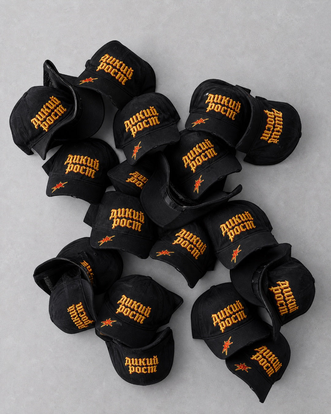 ANTIPROMINDの黒いコットン製ベースボールキャップ。フロントにオレンジのロシア語立体刺繍とバイザーにダメージ加工が施されたユニセックスデザイン。