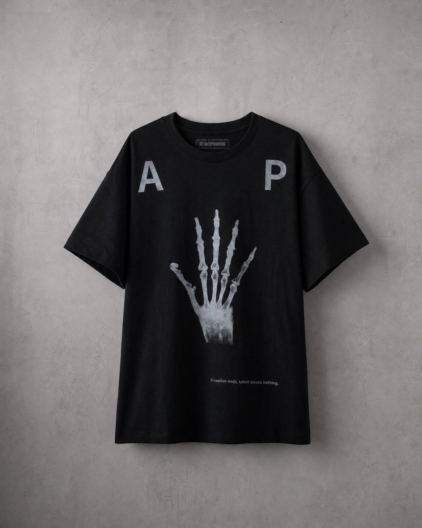 ANTIPROMINDの黒い天竺コットンTシャツ。フロントにスケルトンハンドのグラフィックとタイポグラフィがプリントされたリラックスフィットの半袖シャツ。