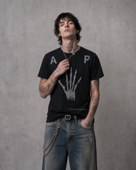 ANTIPROMINDの黒い天竺コットンTシャツ。フロントにスケルトンハンドのグラフィックがプリントされたリラックスフィットのヴィンテージ風デザイン。