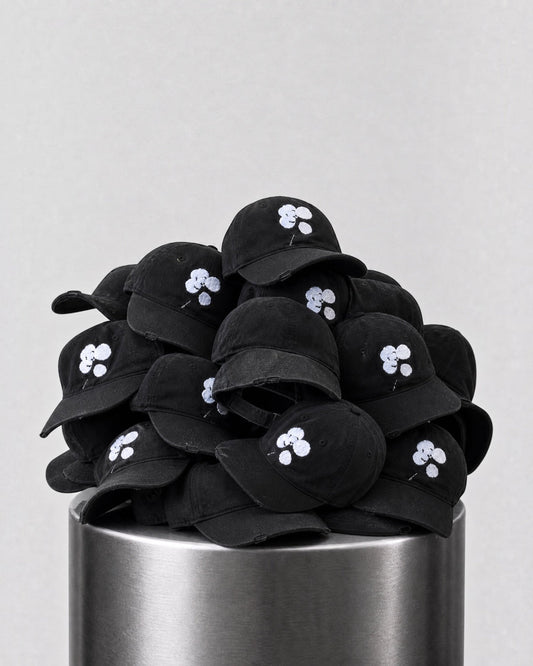 ANTIPROMINDのクローバーロゴが刺繍された黒いコットン製キャップの山。シンプルで洗練されたデザインのベースボールキャップ。