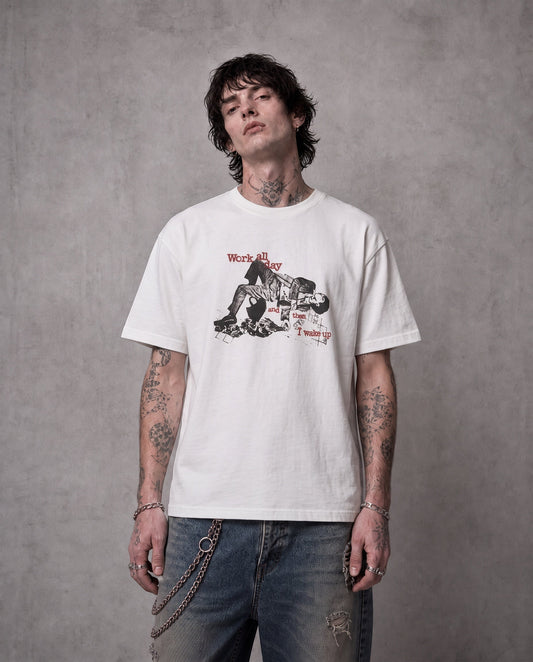 ANTIPROMINDのWORK ALL DAYグラフィックTシャツを着用した男性。柔らかな天竺コットン素材のホワイトTシャツにヴィンテージ風プリントが施されている。