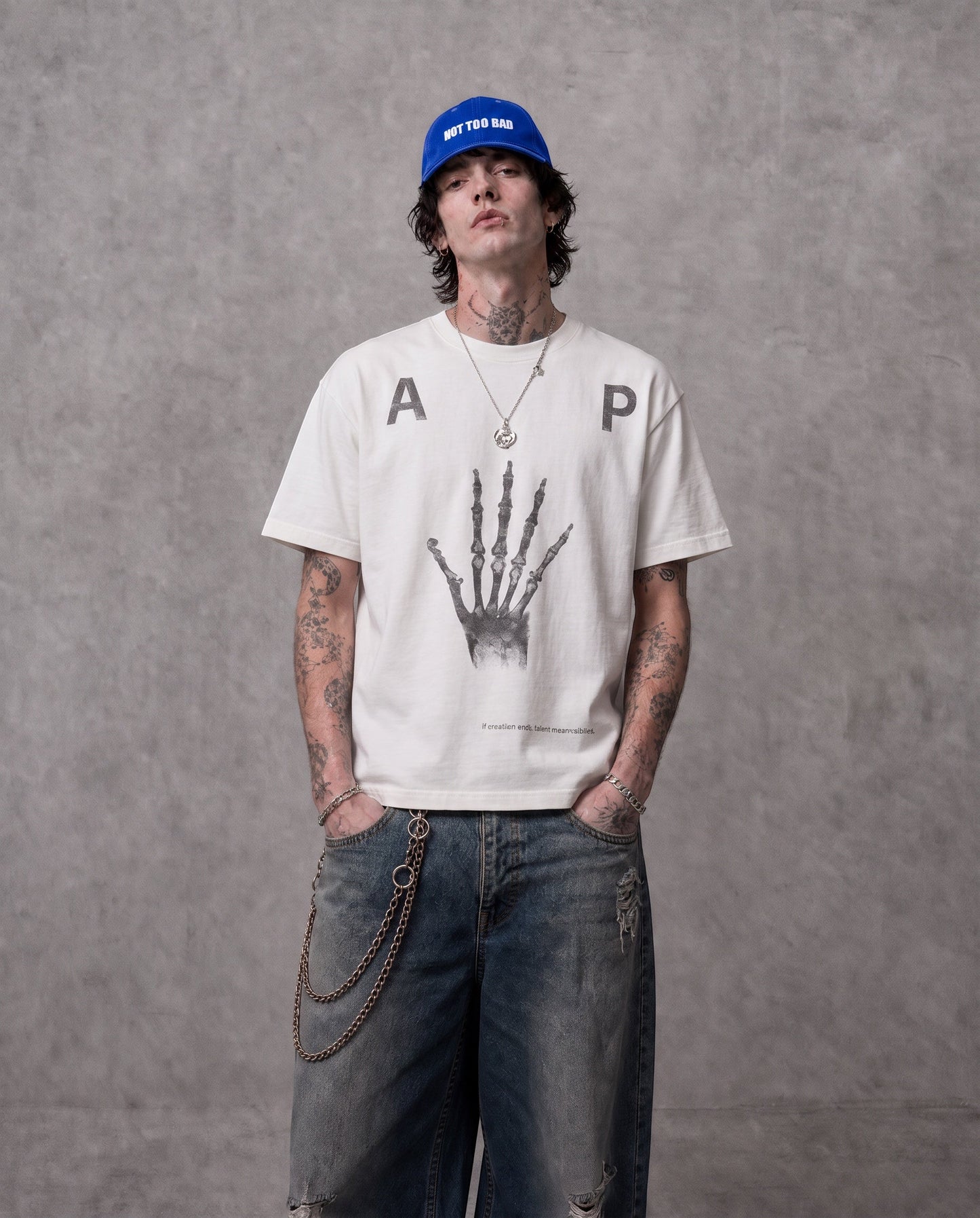 ANTIPROMINDのスケルトンハンドグラフィックがプリントされたホワイトの天竺コットンTシャツを着用した男性モデル