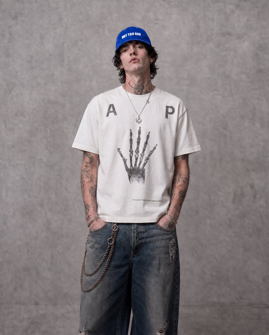 ANTIPROMINDのスケルトンハンドグラフィックがプリントされたホワイトの天竺コットンTシャツを着用した男性モデル