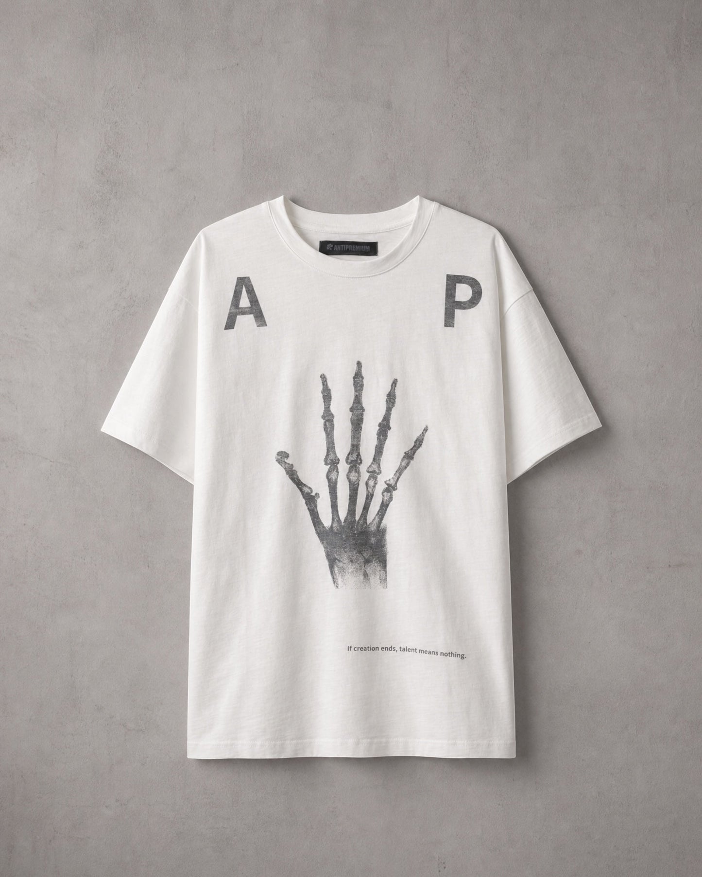 ANTIPROMINDのホワイト天竺コットンTシャツ。フロントにスケルトンハンドのグラフィックとタイポグラフィがプリントされたリラックスフィットの半袖シャツ。