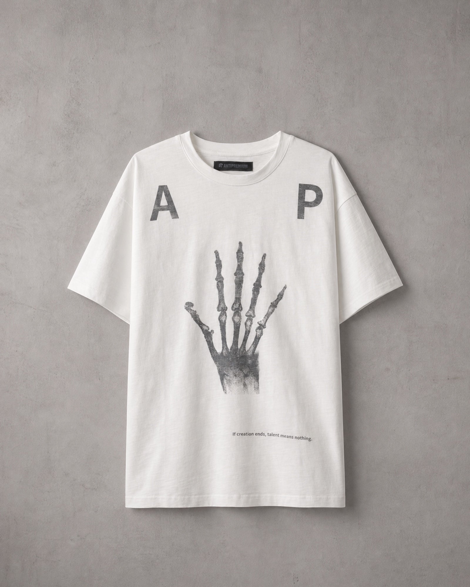 ANTIPROMINDのホワイト天竺コットンTシャツ。フロントにスケルトンハンドのグラフィックとタイポグラフィがプリントされたリラックスフィットの半袖シャツ。