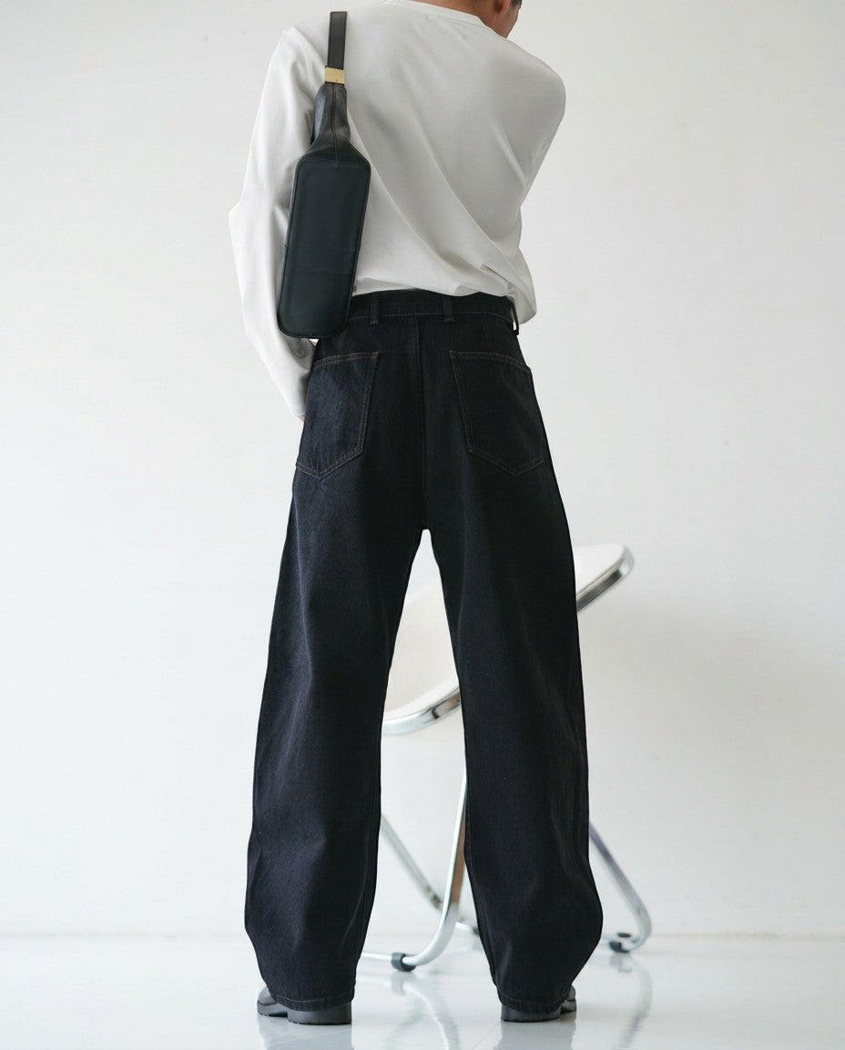BASISの黒のデニムパンツ。カーブしたシルエットで、ゆったりとしたフィット感。