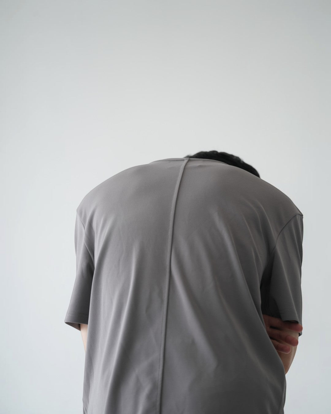 BASISのグレーのトライアセテートTシャツ。リラックスフィット、クルーネック、サイドスリット、バータックが特徴。