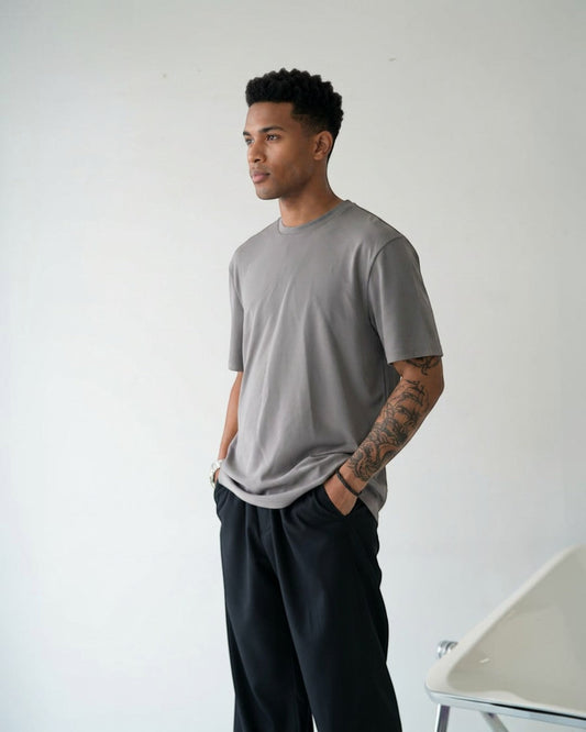 BASISのトライアセテート素材のグレー半袖Tシャツ。リラックスフィット、クルーネック、サイドスリットが特徴。男性モデル着用。