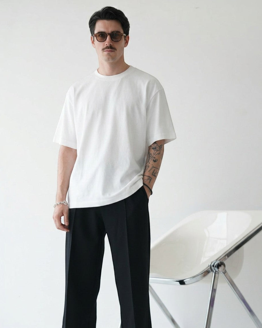 BASISの白いトライアセテート半袖Tシャツ。リラックスフィット、クルーネック、サイドスリット。男性モデル着用。