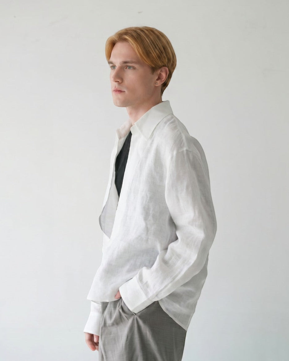 BASISMの白いリネン長袖シャツ。ゆったりとしたシルエットとVネックが特徴。男性モデル着用。