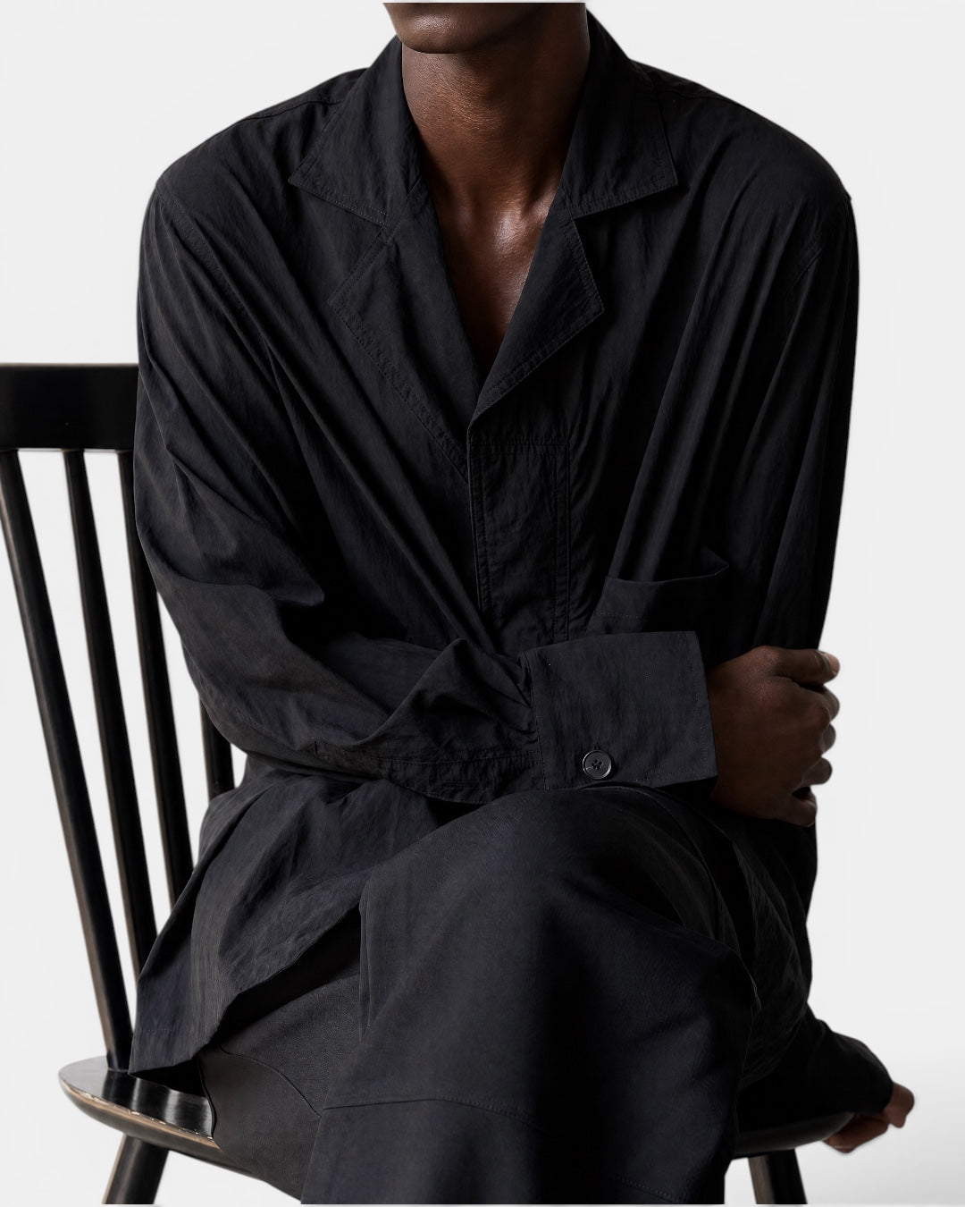 Nameless black suit-collar wide-sleeved shirt on a man sitting on a chair.