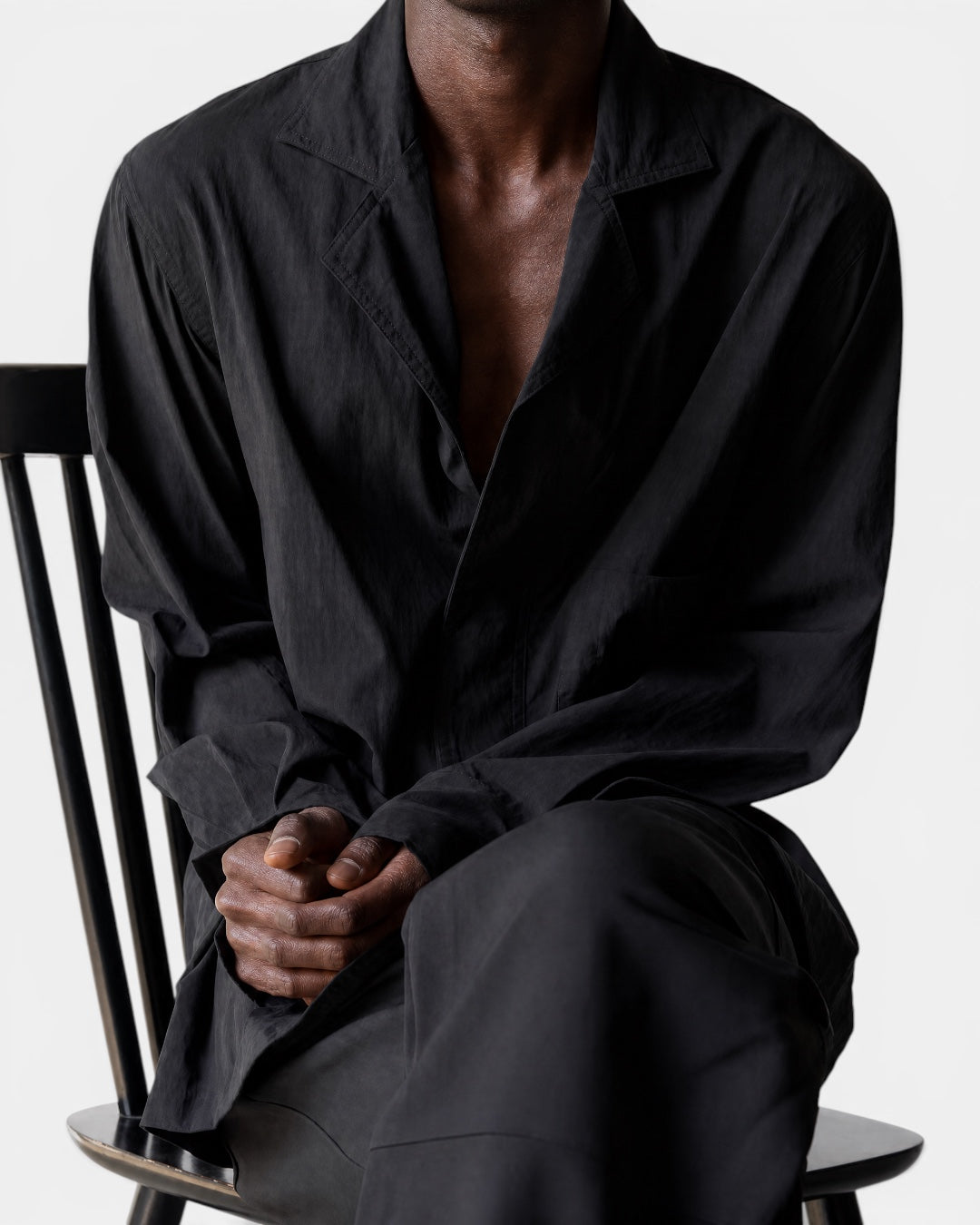 Black suit-collar wide-sleeved shirt by NAMELESS, worn by a man sitting on a chair.