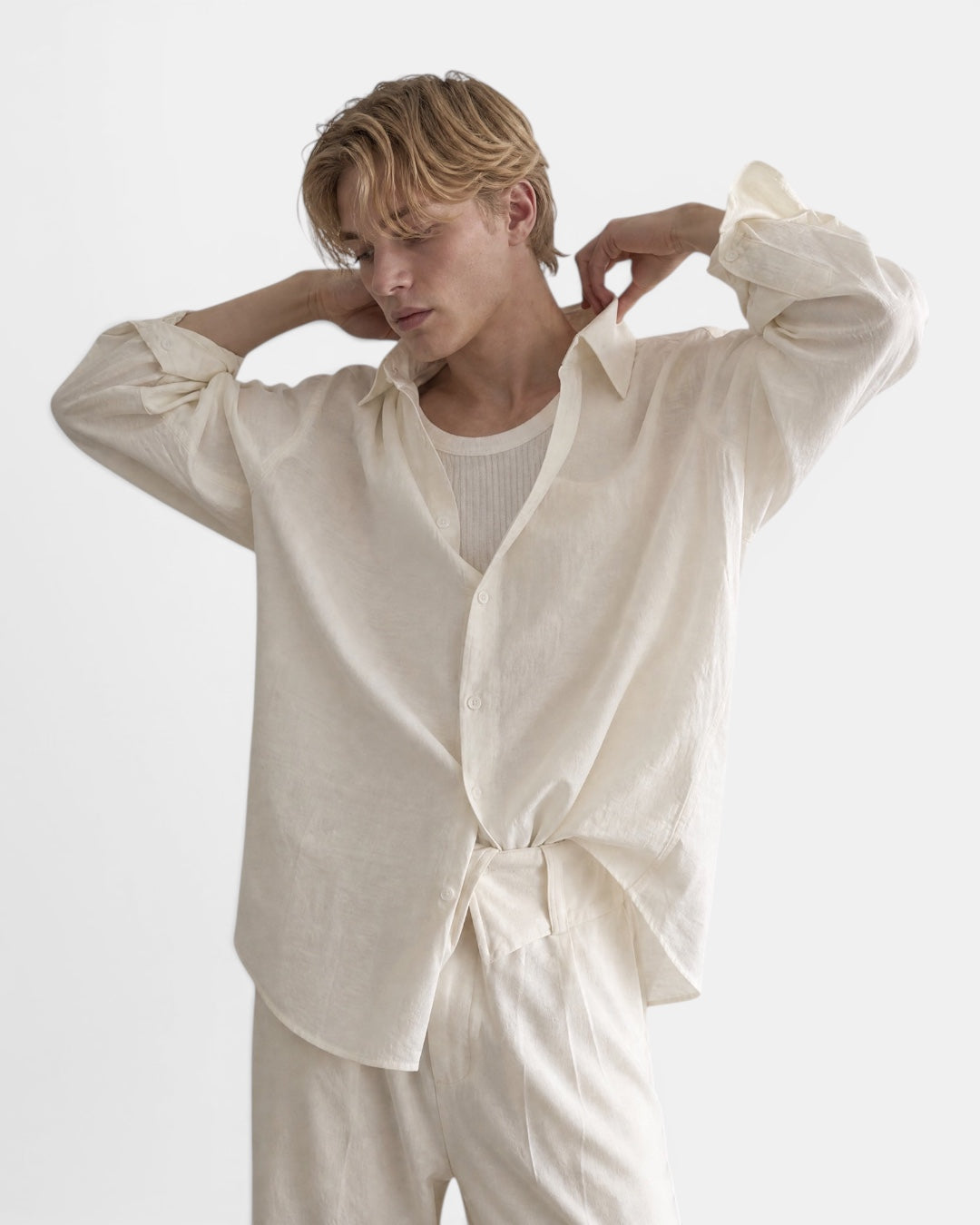 NAMELESS cream textured long sleeve oversized shirt worn by a male model with blonde hair, styled with a white tank top and matching trousers.