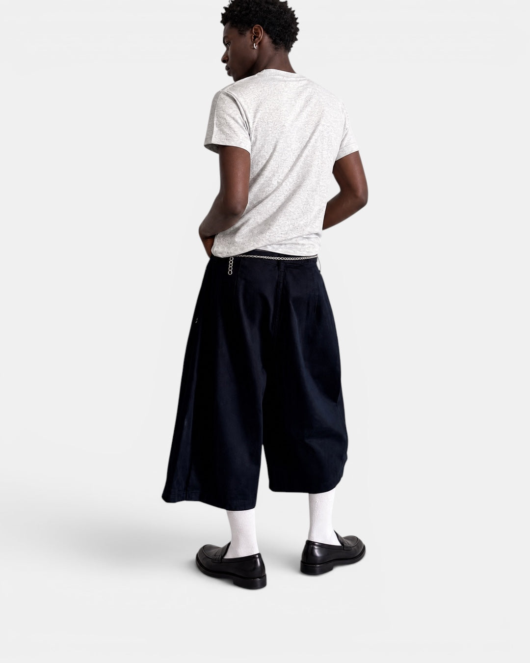Nameless navy blue three-dimensional tailored wide-leg shorts on a man wearing a grey t-shirt.