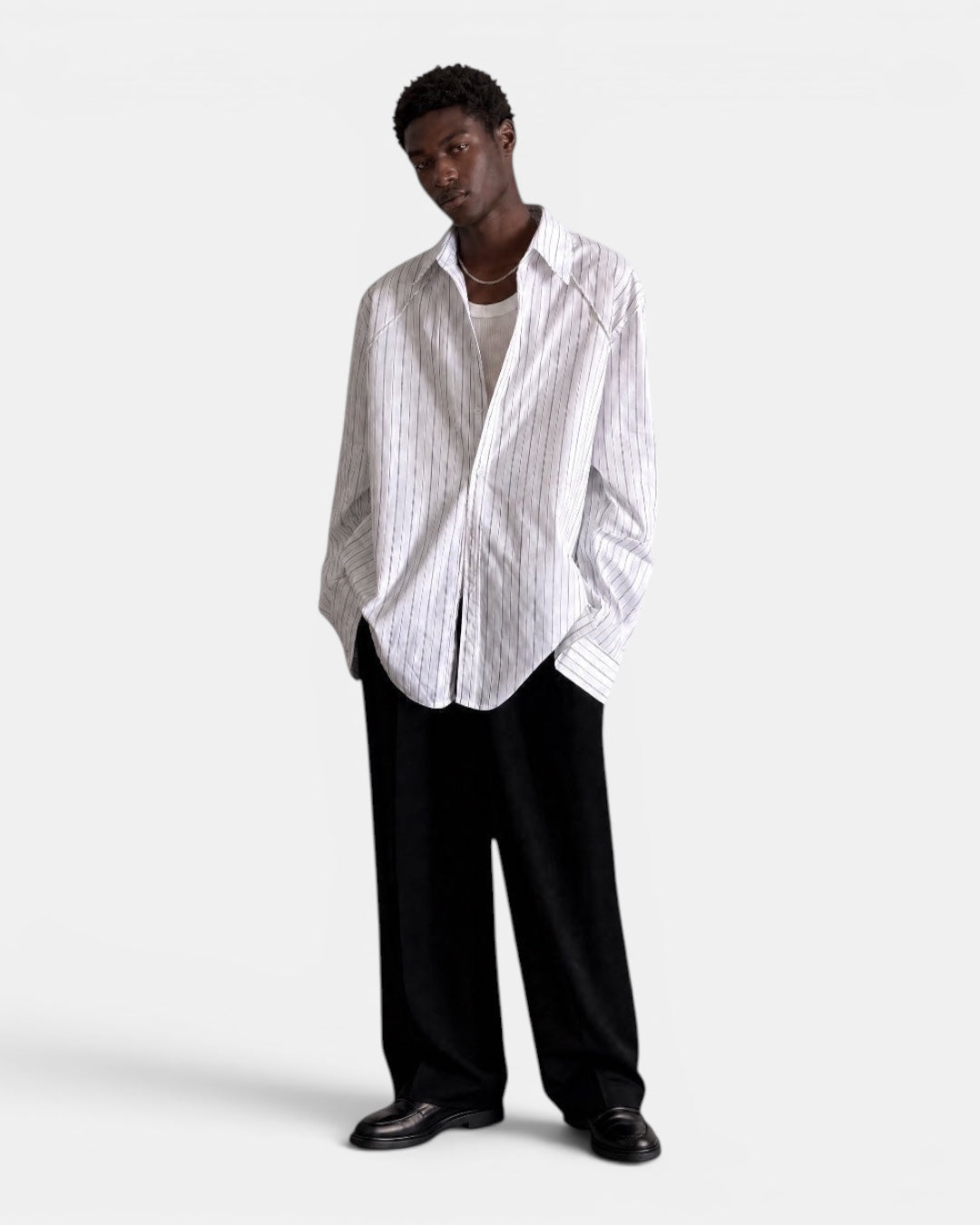 NAMELESS white long-sleeved shirt with subtle blue pinstripes, worn by a male model with black trousers.