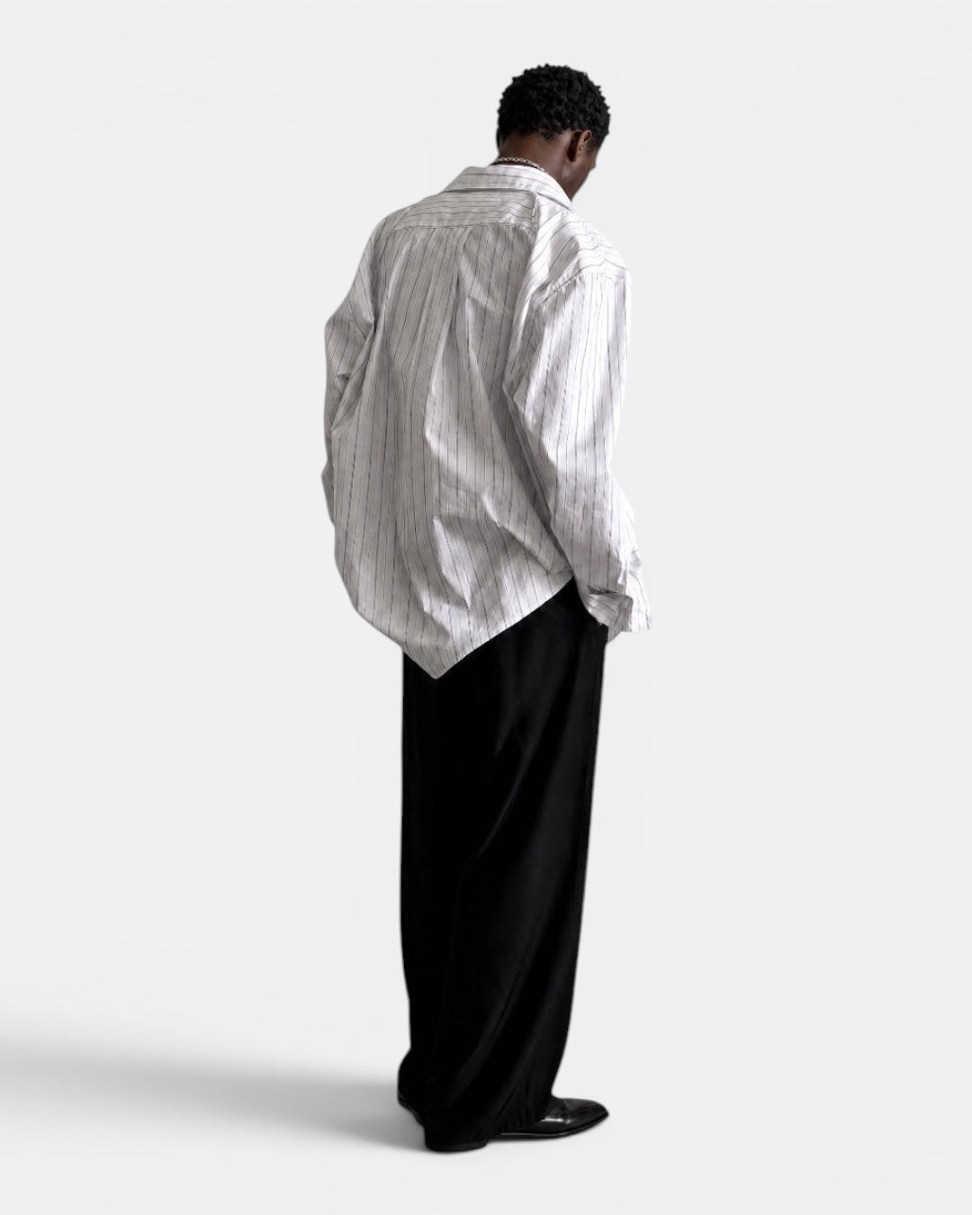 NAMELESS white pinstriped long-sleeved oversized shirt worn by a man with black pants.